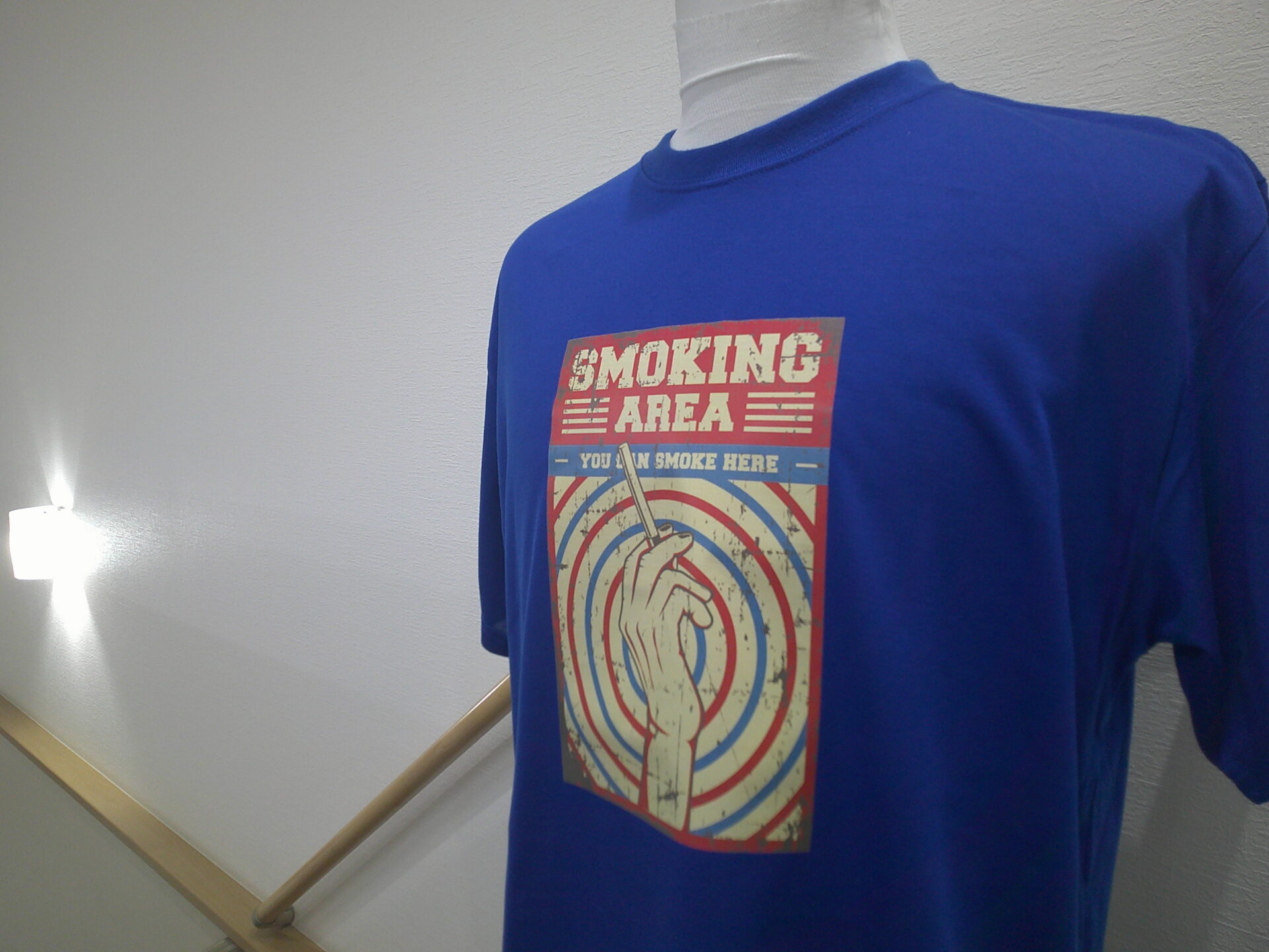 青のTシャツ前面に大きく看板風ロゴをグループリントした制作実績。