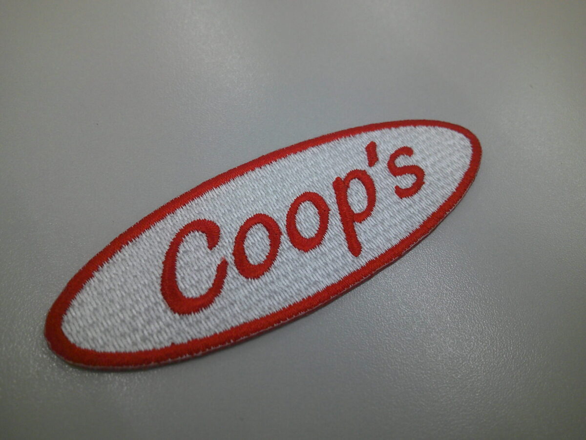 楕円形の文字ワッペン。白ベースに赤の文字とフチ。