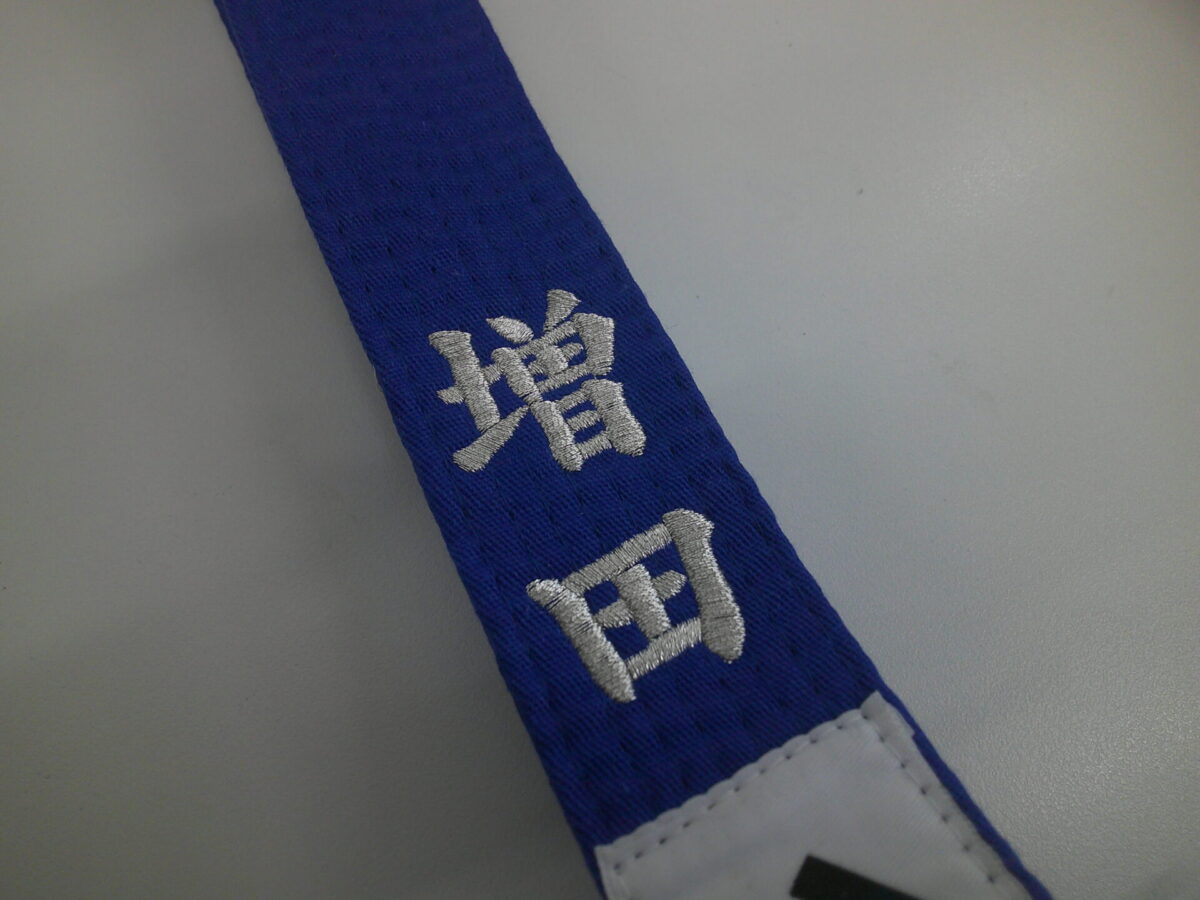 青の空手帯に楷書体(銀糸)で苗字のみを刺繍した制作実績。