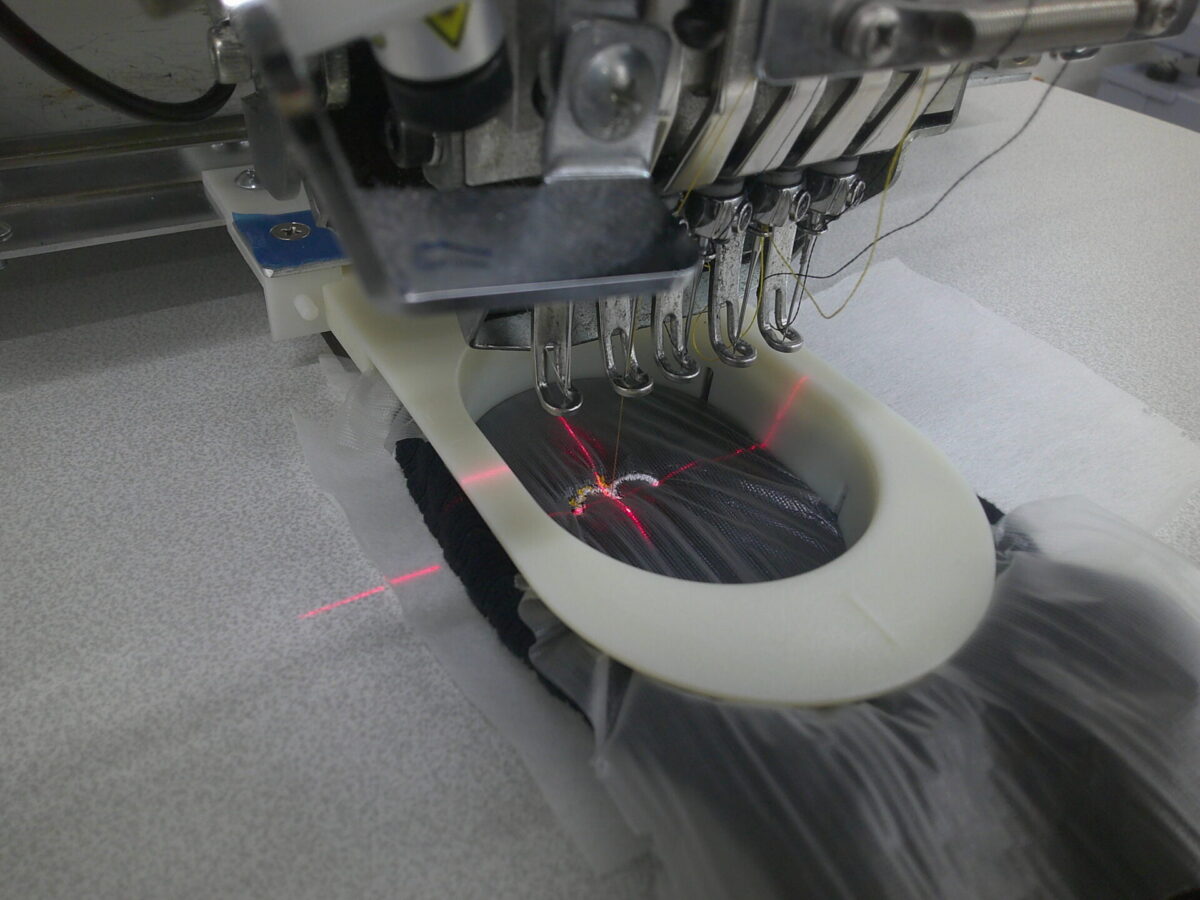 靴下枠(靴下専用の刺繍枠)を使用し、ロゴ刺繍を制作している作業工程