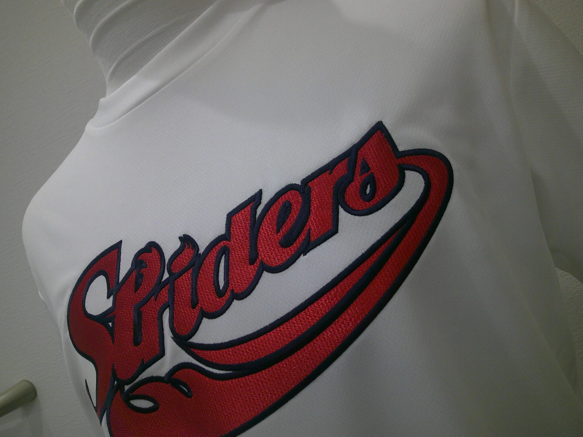 Tシャツ前面に英字の筆記体ロゴを紺糸で縁取り刺繍した制作実績。