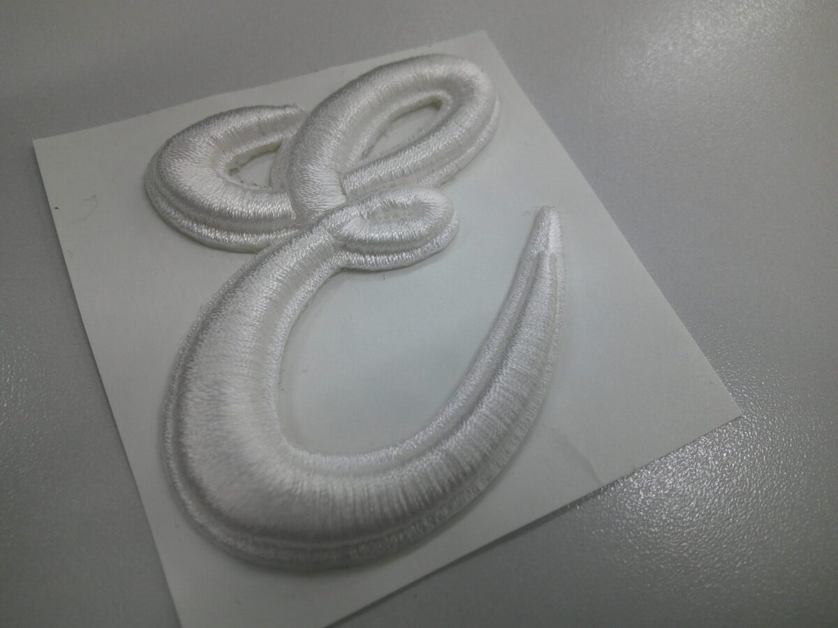 大きな筆記体の「E」の文字を白糸で3D刺繍ワッペンとして製作した加工実績。