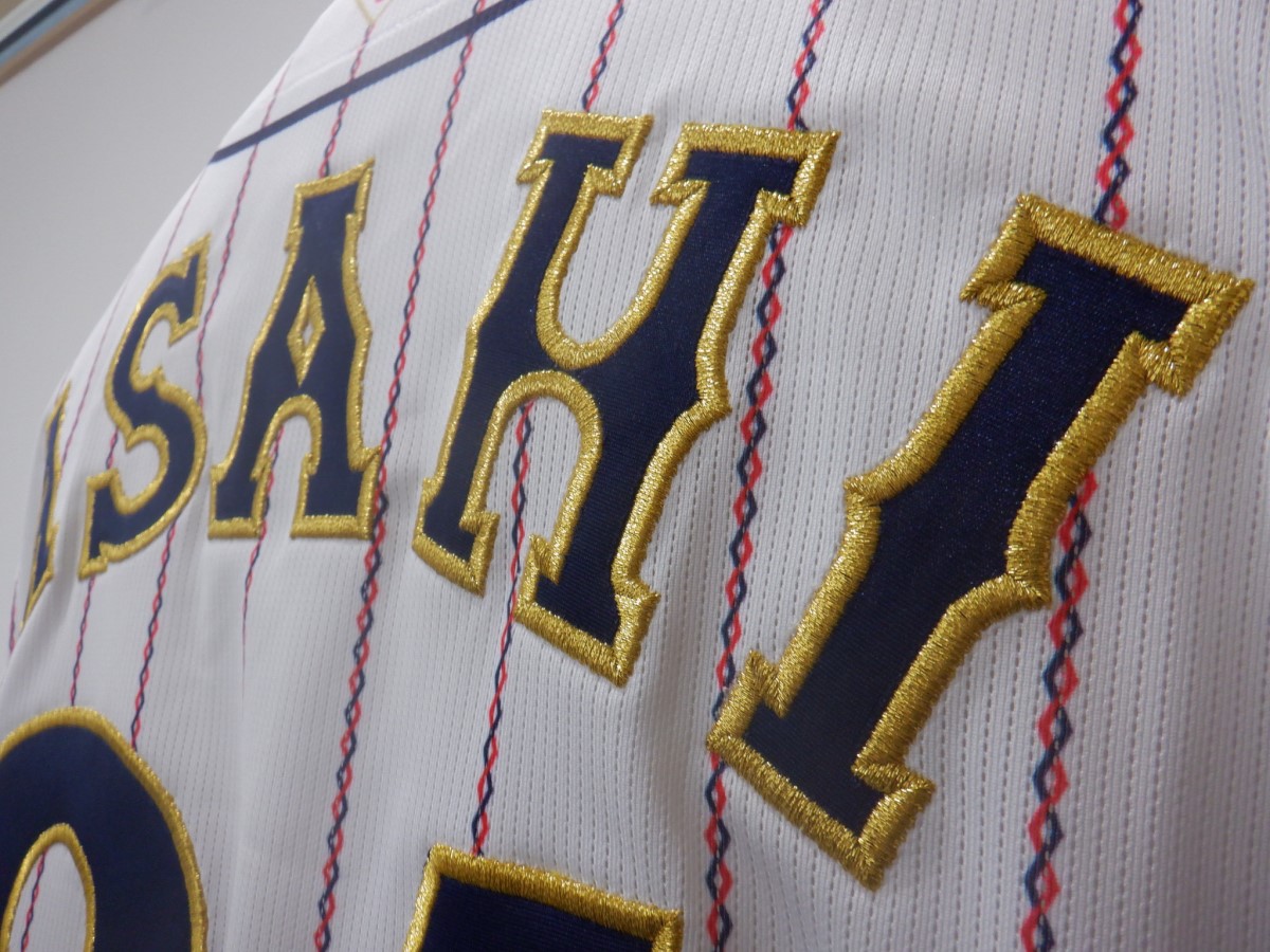 野球ユニフォームの背中に紺生地をベースにした金糸の縁取り刺繍の制作実績。