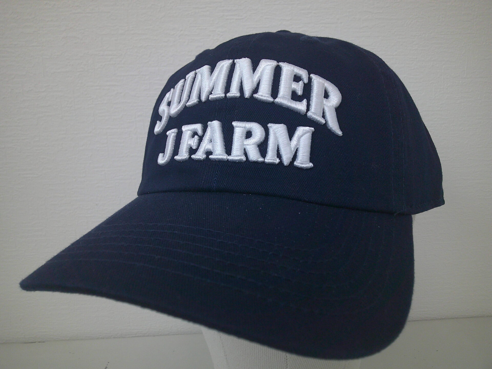 ネイビーの帽子フロントに「SUMMER J FARM」と白糸で3D刺繍を加工した制作実績。