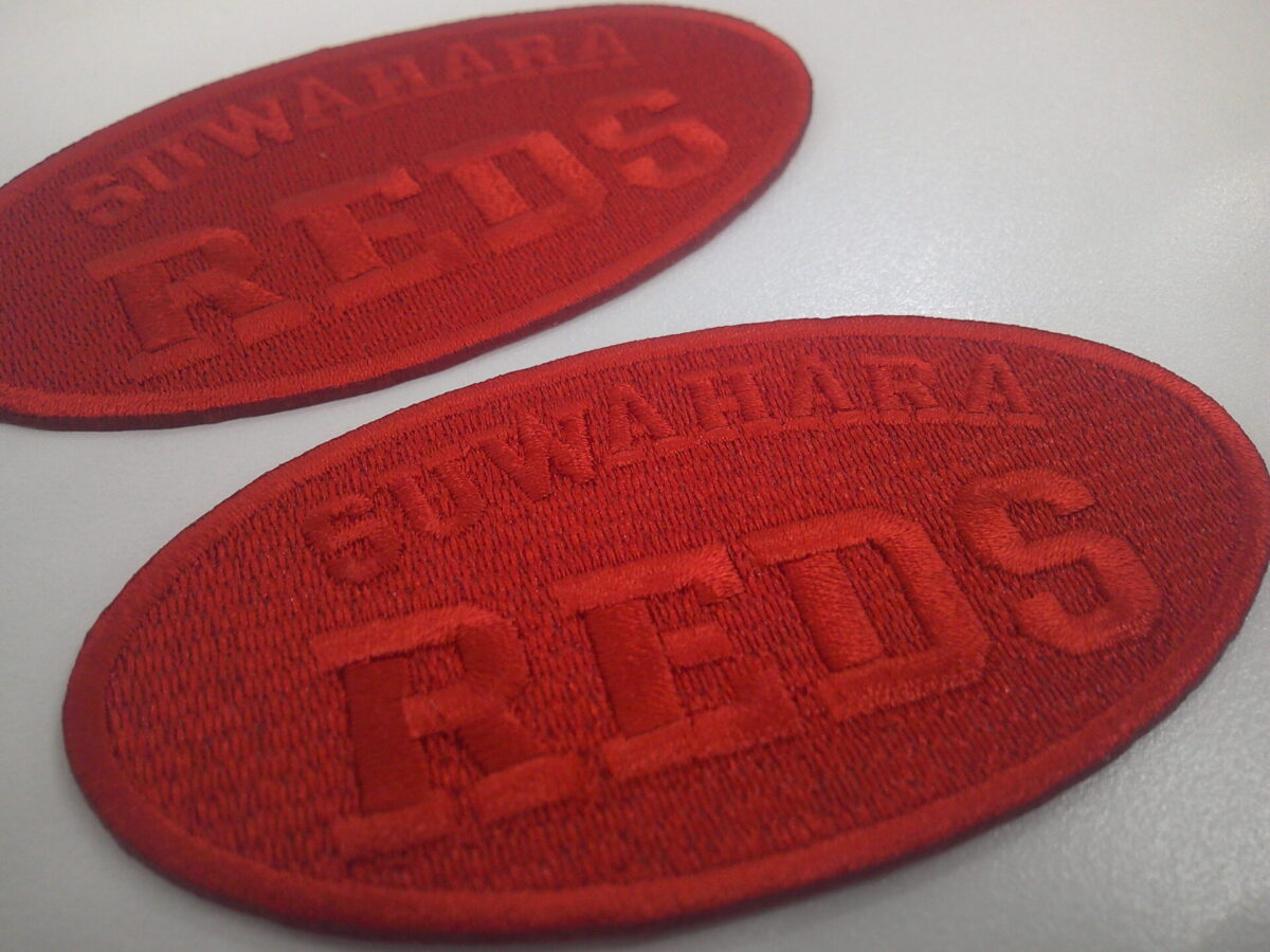 赤の生地に赤の糸で刺繍した、同色系表現をした文字ワッペンの制作実績。