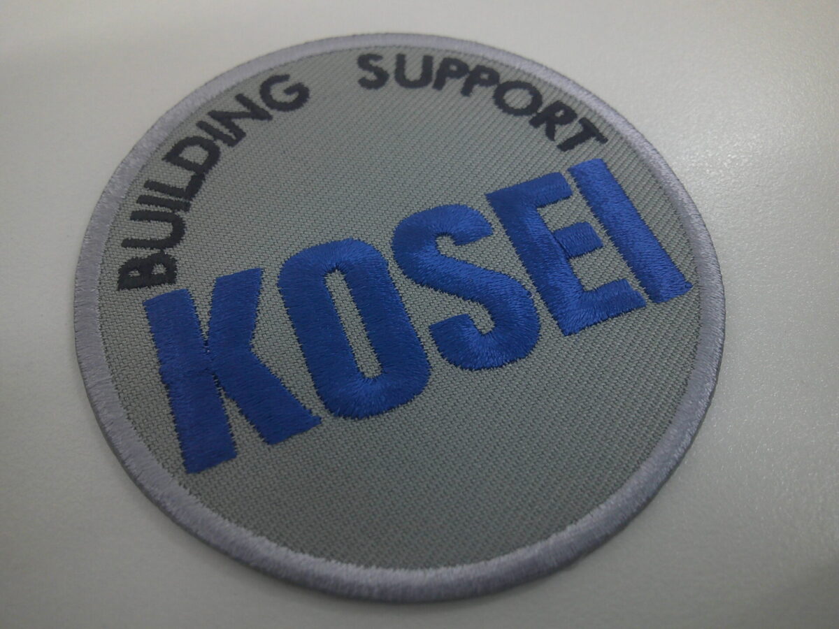 グレーのツイル生地に会社名が大きく刺繍された、文字ワッペンの制作実績。