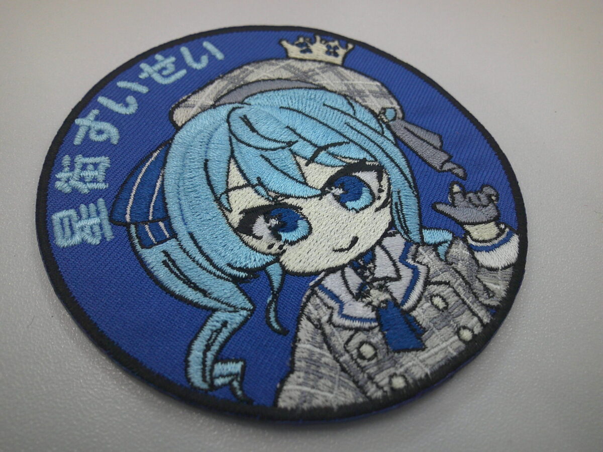 ブルーのツイル生地をベースに青髪の可愛らしい女の子のキャラクターを大きく刺繍した、オリジナル刺繍ワッペンの制作実績。