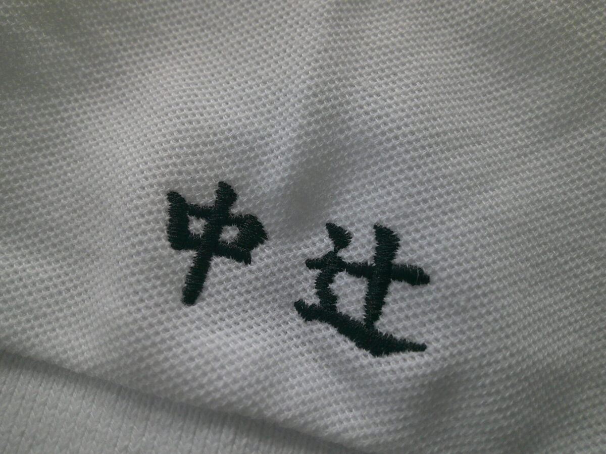 ポロシャツ左袖口に苗字を黒糸で刺繍した制作事例。