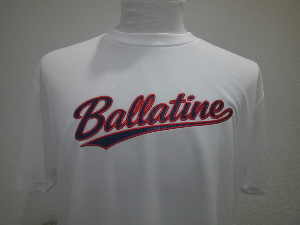 白のTシャツの胸中央に紺生地・赤糸で「Ballatine」の文字を縁取り刺繍した作品。正面から全体を撮影したもの。