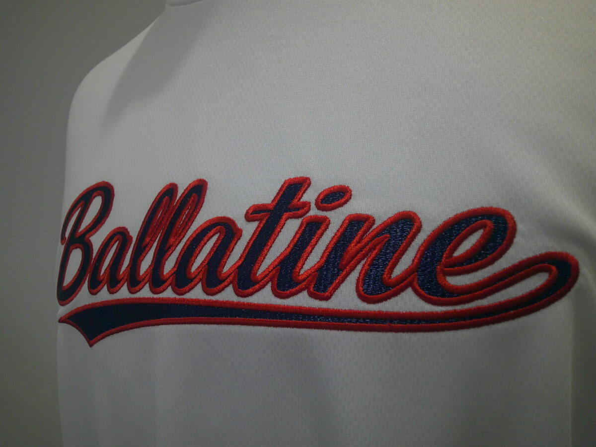 白のTシャツの胸中央に紺生地・赤糸で「Ballatine」の文字を縁取り刺繍した作品。右側から撮影したアップ。